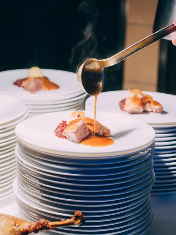 Küchenparty im Louis C. Jacob Eine Person gießt Sauce über einen Teller mit Essen.