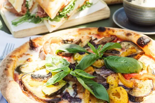 Gemüsepizza Pizza mit Gemüse und Basilikum auf einem Tisch