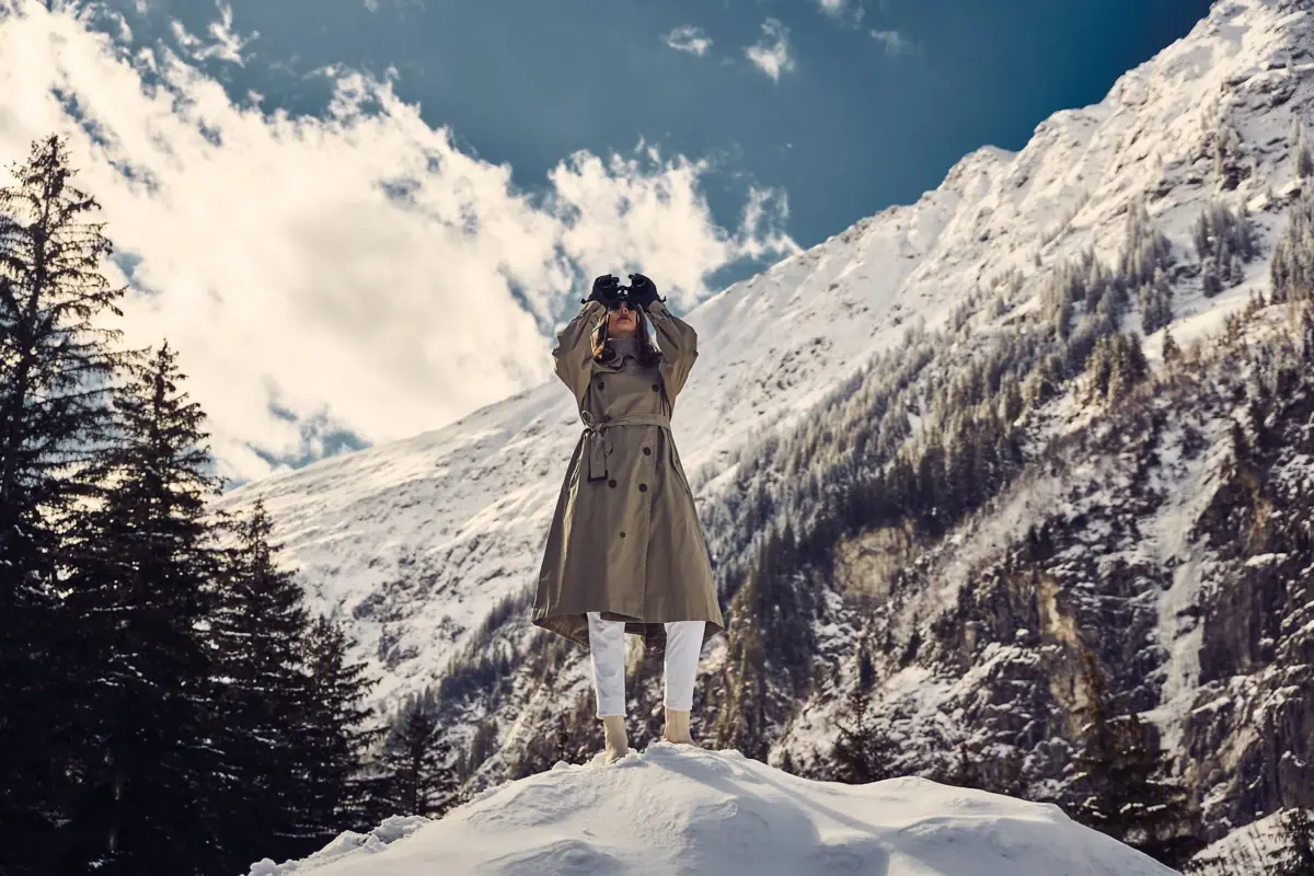 Spaziergang in Bad Gastein Eine Frau steht auf einem verschneiten Berg mit Fernglas.