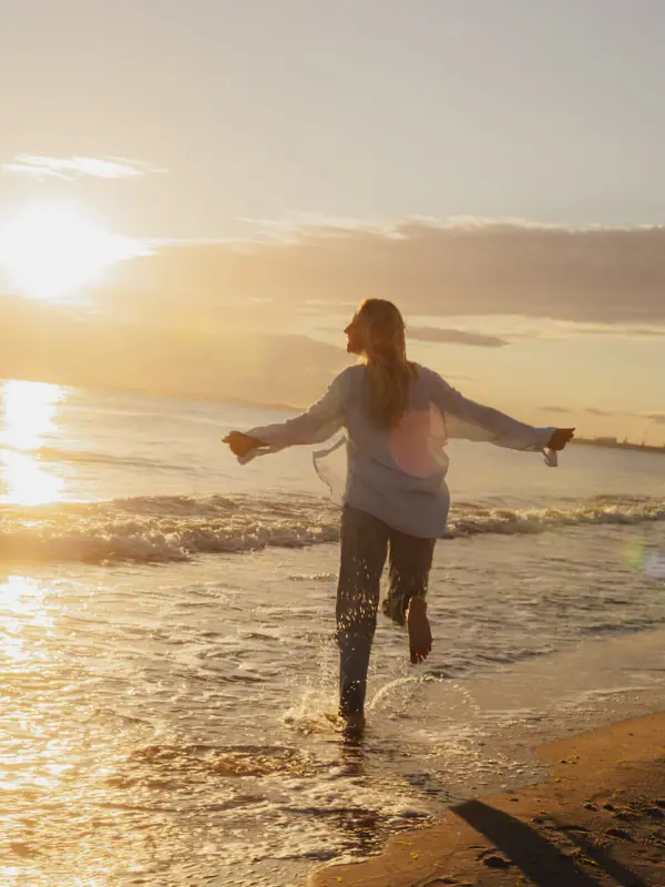 Sonnenaufgang Eine Frau läuft bei Sonnenaufgang am Strand der Ostsee entlang.