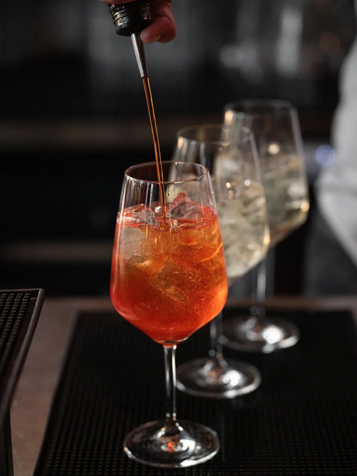 Aperol Eine Person gießt ein alkoholisches Getränk in ein Glas ein.