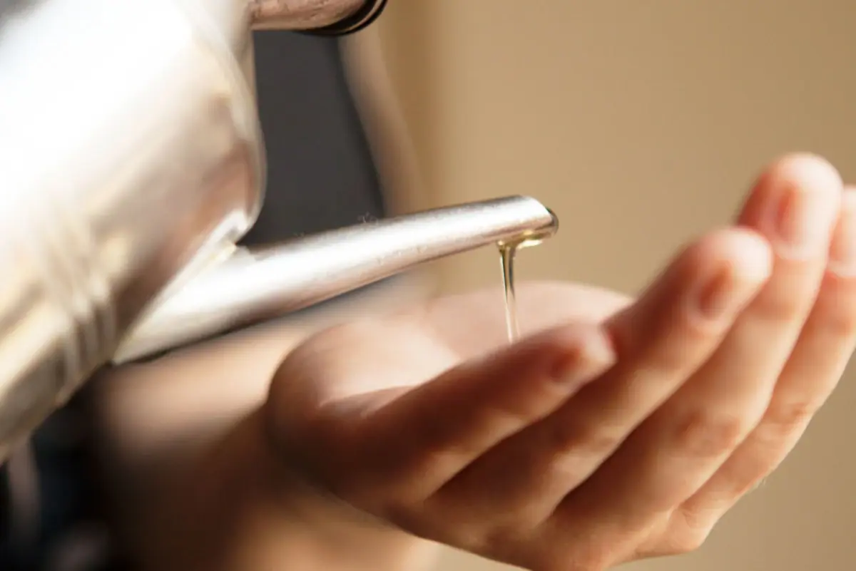 Massage Eine Person gießt Flüssigkeit in ihre Hand.