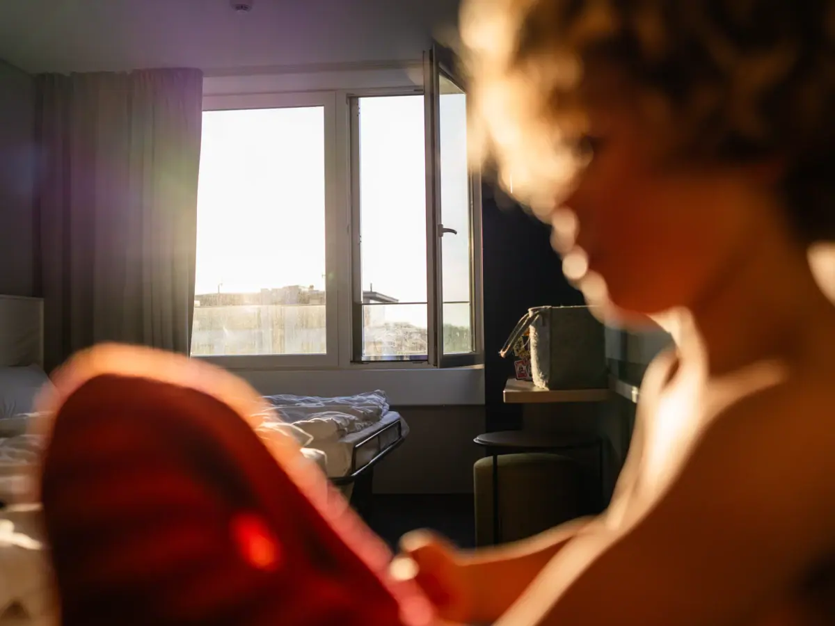 Hotelzimmer im aja Warnemünde Eine Frau im Vordergrund und ein Hotelzimmer mit Fenster im Hintergrund