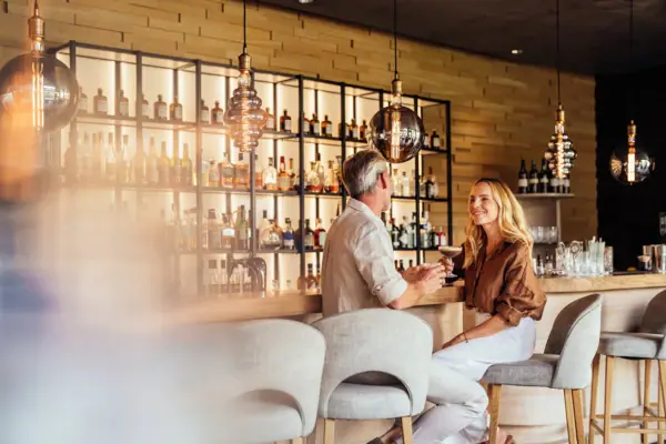 Hotelbar Ifen Kleinwalsertal Ein Mann und eine Frau sitzen an der Hotelbar im A-ROSA Ifen Hotel im Kleinwalsertal.
