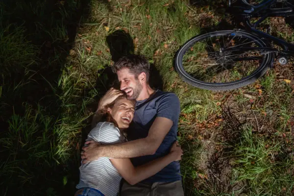 Radtour Ein Mann und eine Frau liegen auf Gras neben einem Fahrrad.