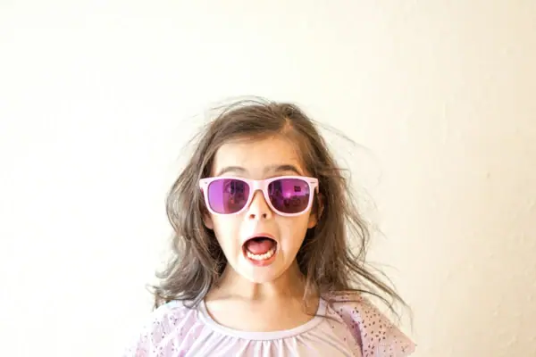 Mädchen mit pinker Sonnenbrille macht eine Grimasse.