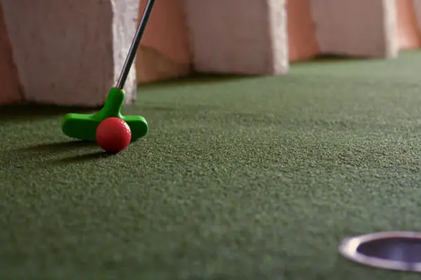 Golfschläger und Golfball auf grünem Untergrund