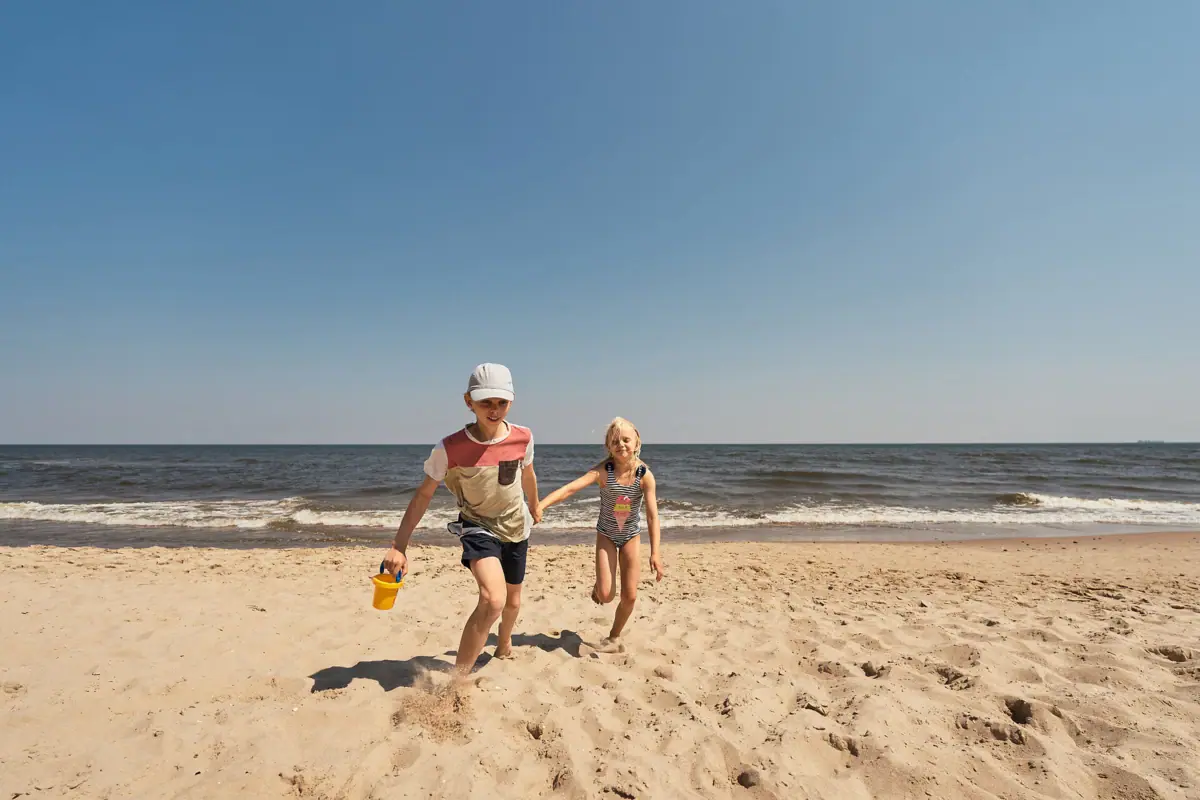Ein Junge und ein Mädchen rennen am Strand.